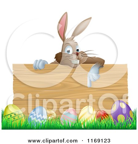 Cartoon of a Brown Easter Bunny Pointing down at a Wood Sign over Eggs in Grass - Royalty Free Vector Clipart by AtStockIllustration