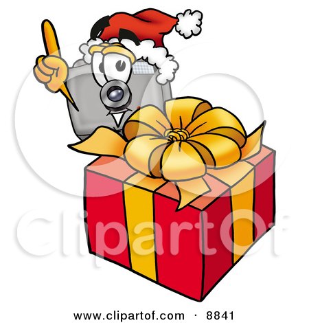Clipart Picture of a Camera Mascot Cartoon Character Standing by a Christmas Present by Mascot Junction