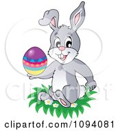 Clipart Easter Bunny Holding An Egg And Sitting In Grass Royalty Free Vector Illustration