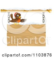 Christmas Robin With A Santa Hat Pointing On A Snow Covered Wooden Sign