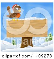 Poster, Art Print Of Christmas Robin With A Santa Hat Perched On A Blank Wooden Sign In The Snow