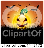 Evil Halloween Jackolantern Pumpkin With Flying Bats Against An Orange Sunset
