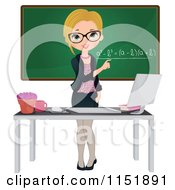 Female Math Teacher At A Desk With A Computer By A Chalkboard