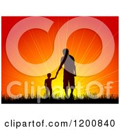 Silhouetted Boy Holding Hands With A Man Father And Son Walking In Grass Towards An Orange Sunset