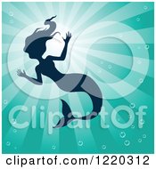 Clipart Of A Silhouetted Swimming Mermaid Over Turquoise Rays Royalty Free Vector Illustration by cidepix