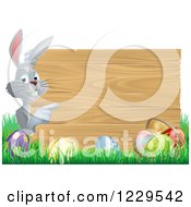Poster, Art Print Of Gray Bunny Pointing To A Wood Sign With Grass And Easter Eggs
