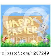 Clipart Of A Gray Bunny Pointing To A Happy Easter Sign With Easter Eggs In Grass Against Blue Sky Royalty Free Vector Illustration