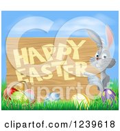 Clipart Of A Happy Gray Bunny Rabbit Pointing To A Happy Easter Sign Over Eggs Grass And Sky Royalty Free Vector Illustration
