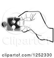 Clipart Of A Black And White Hand Holding A Jigsaw Puzzle Piece Royalty Free Vector Illustration