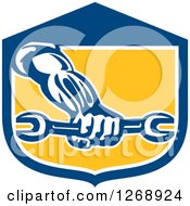 Clipart Of A Retro Strong Mechanic Hand Holding A Wrench In A Blue White And Yellow Shield Royalty Free Vector Illustration