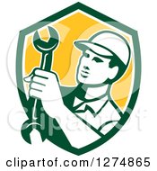 Clipart Of A Retro Mechanic Man Holding A Spanner Wrench In A Green White And Yellow Shield Royalty Free Vector Illustration