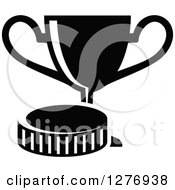 Clipart Of A Black And White Trophy Cup And Hockey Puck Royalty Free Vector Illustration