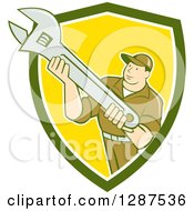 Clipart Of A Retro Cartoon Male Mechanic Holding An Adjustable Wrench In A Green White And Yellow Shield Royalty Free Vector Illustration