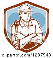 Clipart Of A Retro Male Mechanic Holding A Wrench With Folded Arms In A Brown White And Blue Shield Royalty Free Vector Illustration