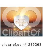 Clipart Of Happy Valentines Day Text On A White Heart With Magic Flares Over A Blurred Ocean Sunset Royalty Free Vector Illustration