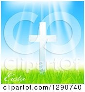 Sun Rays Shining Down On A White Cross With Easter Text Blue Sky And Green Grass