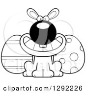 Holiday Clipart Of A Black And White Cartoon Happy Grinning Easter Bunny With Eggs Royalty Free Lineart Vector Illustration