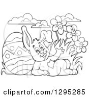 Clipart Of A Black And White Easter Bunny Rabbit Waving And Leaning Against A Giant Easter Egg Royalty Free Vector Illustration