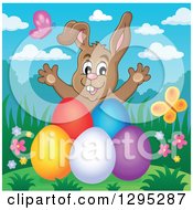 Poster, Art Print Of Happy Brown Easter Bunny Rabbit Popping Out Behind Colorful Easter Eggs On A Hill