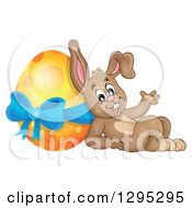 Poster, Art Print Of Brown Easter Bunny Rabbit Waving And Leaning Against A Giant Yellow Easter Egg