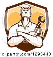 Clipart Of A Retro Male Mechanic With Folded Arms Holding A Wrench In A Brown White And Yellow Shield Royalty Free Vector Illustration