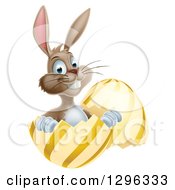 Poster, Art Print Of Happy Brown Easter Bunny Sitting And Pointing In A Gold And Yellow Egg Shell