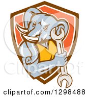Clipart Of A Retro Woodcut Muscular Elephant Man Mechanic Holding A Wrench In Brown White And Orange Shield Royalty Free Vector Illustration