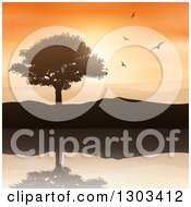 Poster, Art Print Of Silhouetted Tree And Hills With Flying Birds Reflecting In Water Against An Orange Sunset