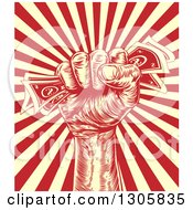 Clipart Of A Retro Engraved Revolutionary Fist Holding Money Over A Red And Yellow Burst Royalty Free Vector Illustration by AtStockIllustration