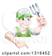 Young Brunette White Male Gardener In Green Holding Up A Garden Fork And Pointing Down Over A Sign