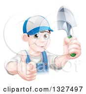 Poster, Art Print Of Young Brunette White Male Gardener In Blue Holding Up A Shovel And Giving A Thumb Up