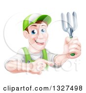 Middle Aged Brunette White Male Gardener In Green Holding Up A Garden Fork And Pointing