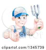 Poster, Art Print Of Happy Young Brunette White Male Gardener In Blue Holding Up A Garden Fork And Thumb