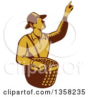 Retro Woodcut Brown And Yellow Male Farm Fruit Picker Worker Pointing And Holding A Basket