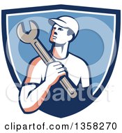 Clipart Of A Retro Male Mechanic Holding A Giant Wrench Over His Shoulder In A Blue And White Shield Royalty Free Vector Illustration