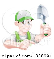 Happy Young Brunette White Male Gardener In Green Pointing And Holding A Shovel