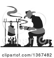 Black Silhouetted Cowboy Kneeling And Making Coffee Over A Camp Fire