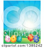 Poster, Art Print Of Background Of Patterned Easter Eggs Grass And Flowers Against A Blue Sky With Sunshine