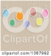 Clipart Of Suspended Patterned Easter Eggs Over A Cardboard Texture With Text Space Royalty Free Vector Illustration by KJ Pargeter