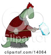 Green Dino In A Coat And Hat Shoveling Snow In Winter