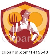 Poster, Art Print Of Retro Male Farmer Or Worker Standing With One Hand In His Pocket And One Hand Holding A Pitchfork In A Red And Orange Shield