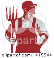 Retro Male Farmer Or Worker Standing With One Hand In His Pocket And One Hand Holding A Pitchfork