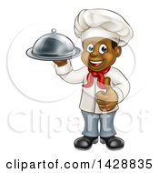 Poster, Art Print Of Happy Young Black Male Chef Holding A Cloche Platter And Giving A Thumb Up