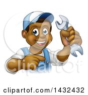 Clipart Of A Cartoon Happy Black Male Mechanic Holding Up A Wrench And Pointing Royalty Free Vector Illustration