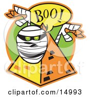 White Mummy With Green Glowing Eyes Peeking Out Of A Pyramid And Screaming Boo Clipart Illustration