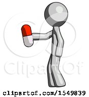 Gray Design Mascot Man Holding Red Pill Walking To Left
