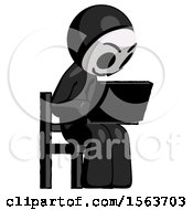 Black Little Anarchist Hacker Man Using Laptop Computer While Sitting In Chair Angled Right