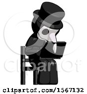 Black Plague Doctor Man Using Laptop Computer While Sitting In Chair Angled Right