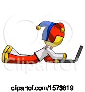 Poster, Art Print Of Yellow Jester Joker Man Using Laptop Computer While Lying On Floor Side View