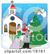 Woman And A Man Singing Christmas Carols In The Snow Outside Of A Church While An Angel Tops A Tree With A Star